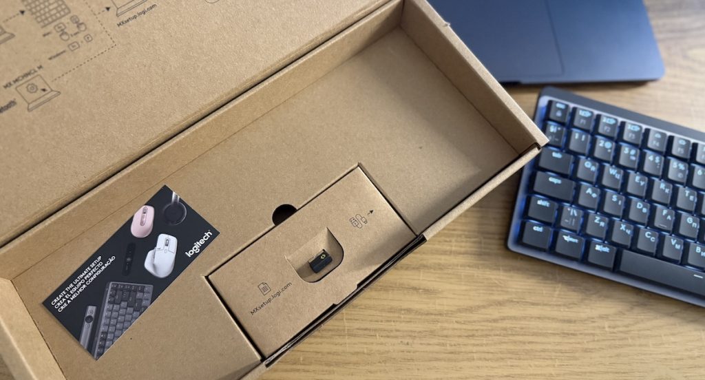 Відкритий картонний ящик з продукцією Logitech, в якому видно механічну клавіатуру, інструкції та ресівер Logi Bolt.