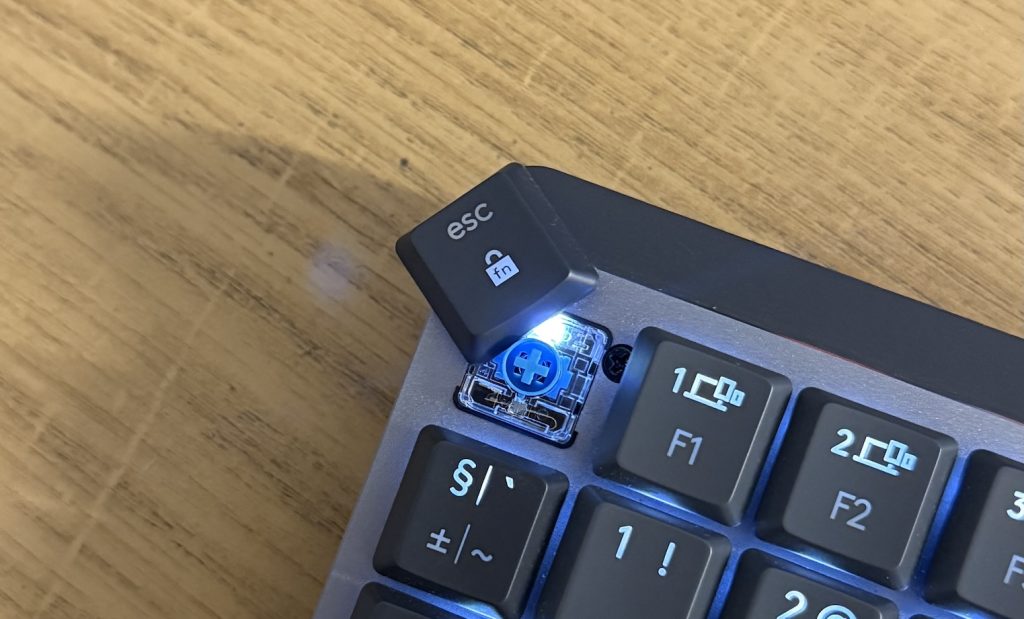 Зображення механічної клавіатури Logitech із знятою клавішею Esc, показуючи підсвітку та ключові деталі під клавішею.
