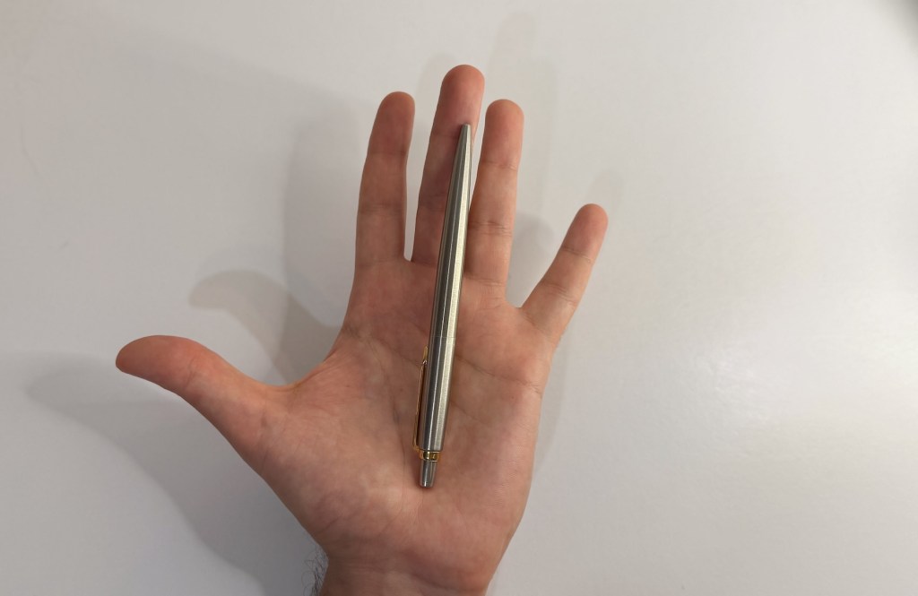 Ручка Parker Jotter, яка тримається в руці, розміщена на долоні. Виготовлена з нержавіючої сталі з позолоченим кліпом.